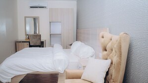 Quarto de hotel com uma cama grande, uma cadeira, uma mesa e um espelho.