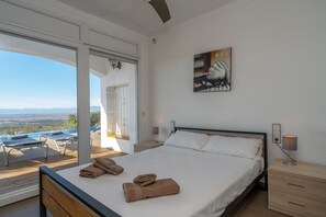 A bedroom with a large bed, a nightstand, a lamp, and a painting on the wall. - Casa Blanca - Exclusive villa with infinity pool and panoramic views (El Mas Fumats)