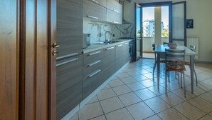 Une cuisine moderne avec des meubles gris, un évier en acier inoxydable et un coin repas comprenant une table et des chaises.