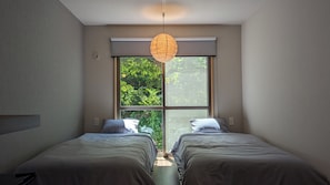 Un dormitorio con dos camas, un ventanal grande y una lámpara colgante.