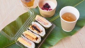 Una comida con sushi, un cuenco de bayas y dos tazas de té sobre una hoja.