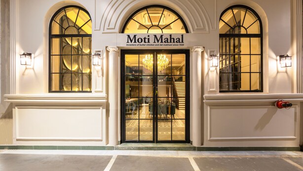 The exterior of Moti Mahal with arched windows and a sign indicating it is an inventor of butter chicken and dal makhani since 1920. - Saltstayz Autograph Connaught Place (New Delhi)