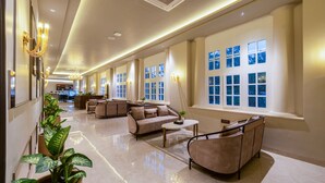 A spacious lobby with a reception desk, seating area, and large windows with multiple panes. - Saltstayz Autograph Connaught Place (New Delhi)