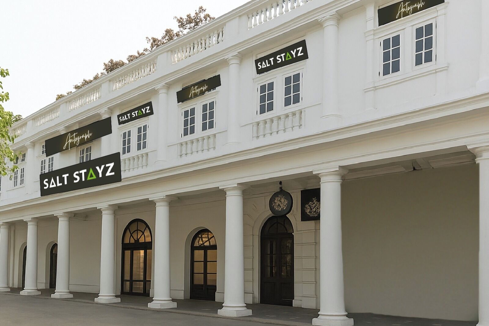 A building with a classic architectural style, featuring a row of columns and arched doorways. The facade includes multiple signs for 'Salt Stayz' and 'Autograph'.