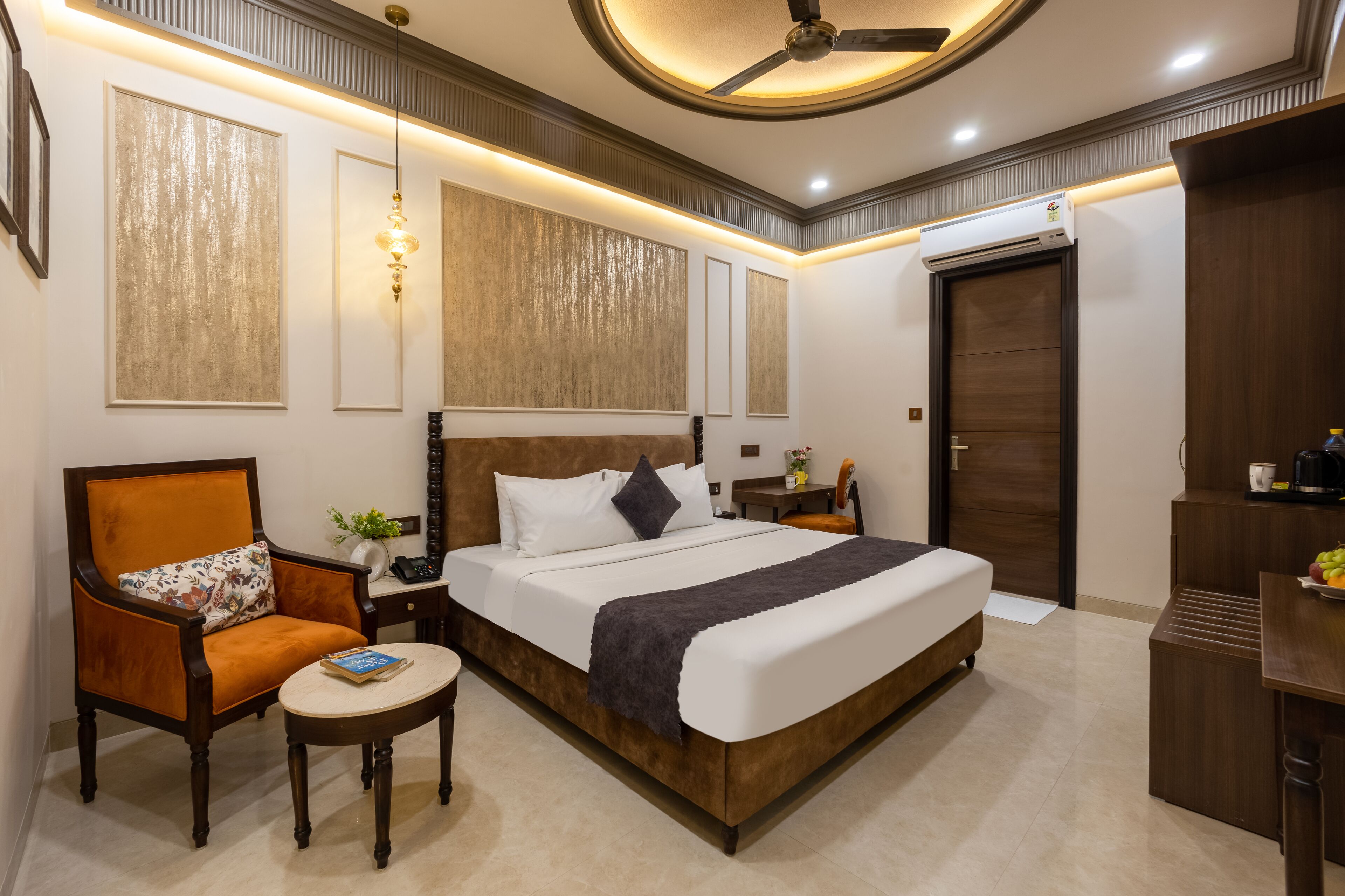 A neatly arranged hotel room with a large bed, a chair, a small table, and a wardrobe.