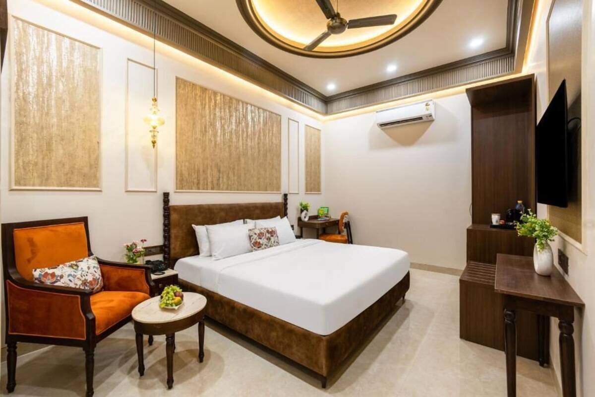 Una habitación de hotel con una cama grande, una silla, una mesita y un televisor.