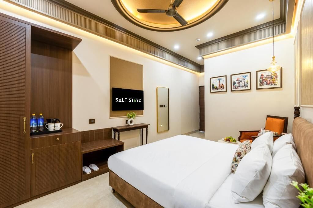 Une chambre d’hôtel avec un lit, une télévision, une armoire et une petite table sur laquelle est posée une plante.
