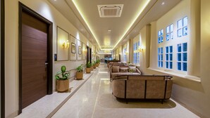 A hotel lobby with a long corridor, seating area, and large windows. - Saltstayz Autograph Connaught Place (New Delhi)