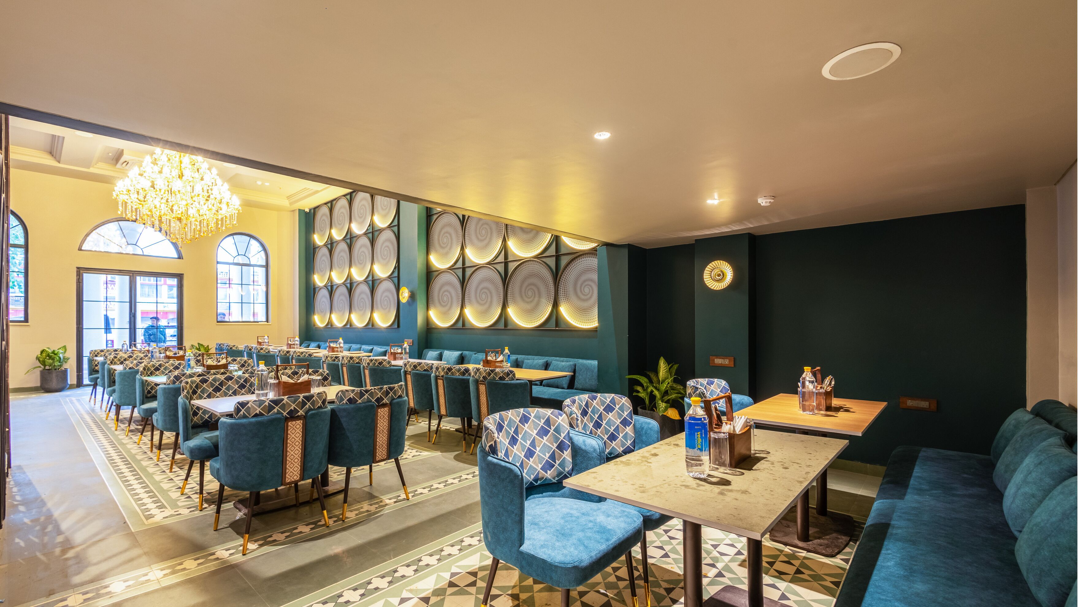 Un restaurant moderne avec des sièges rembourrés en tissu bleu, des motifs décoratifs sur les murs et un lustre.