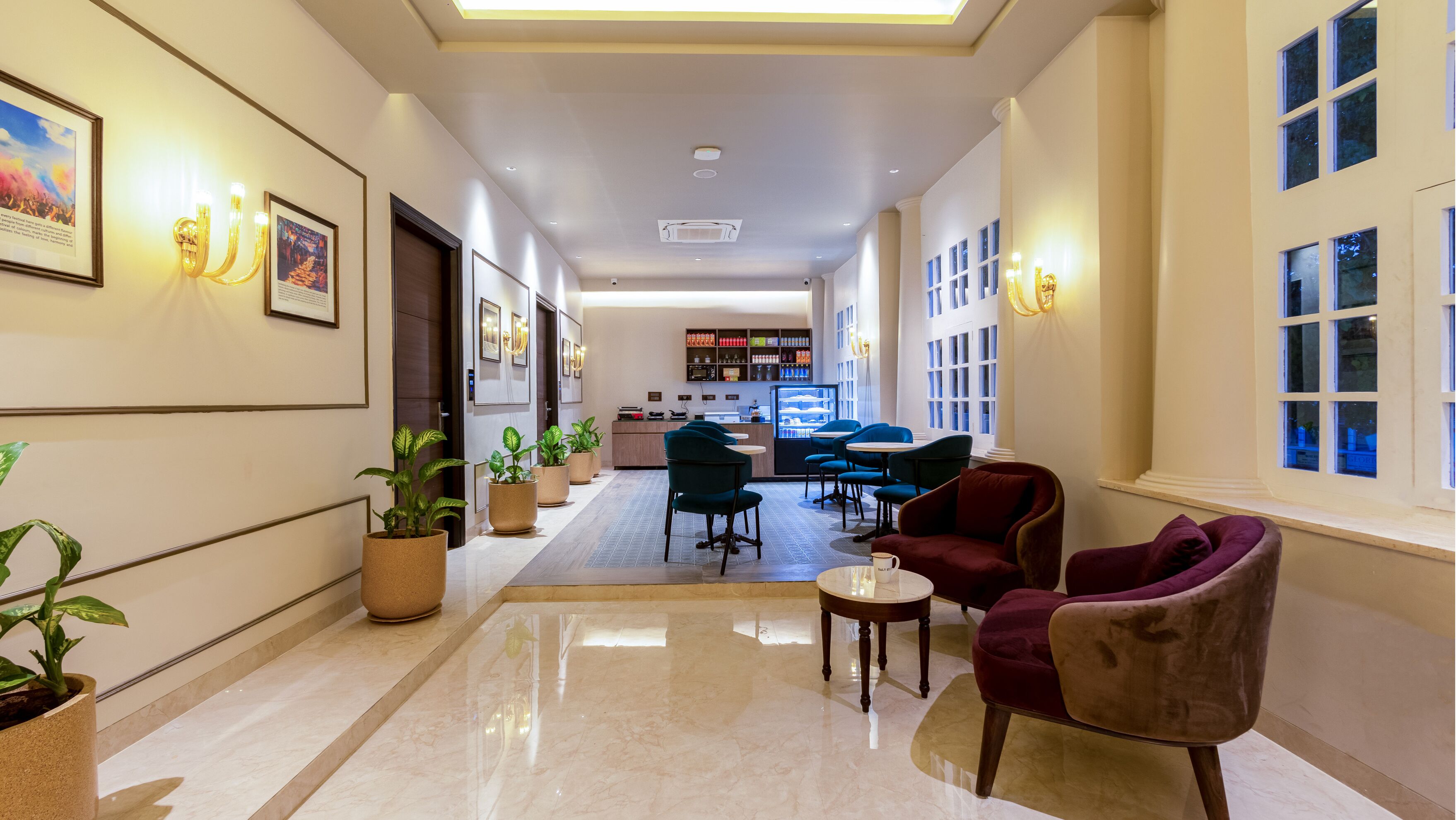 Et hotel lobby med en lang gang, siddeområde og et tekøkken.