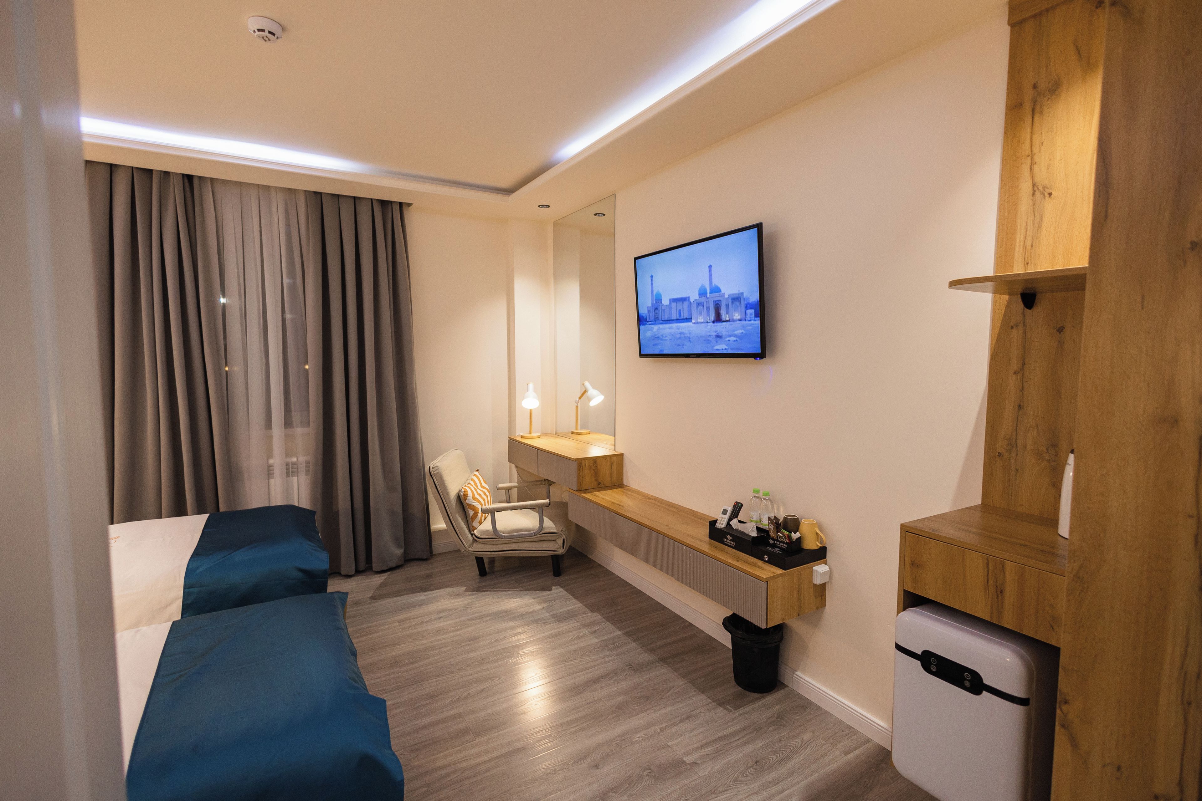 Une chambre d’hôtel équipée d’un lit, d’un bureau, d’une chaise, d’une télévision et d’un petit réfrigérateur.