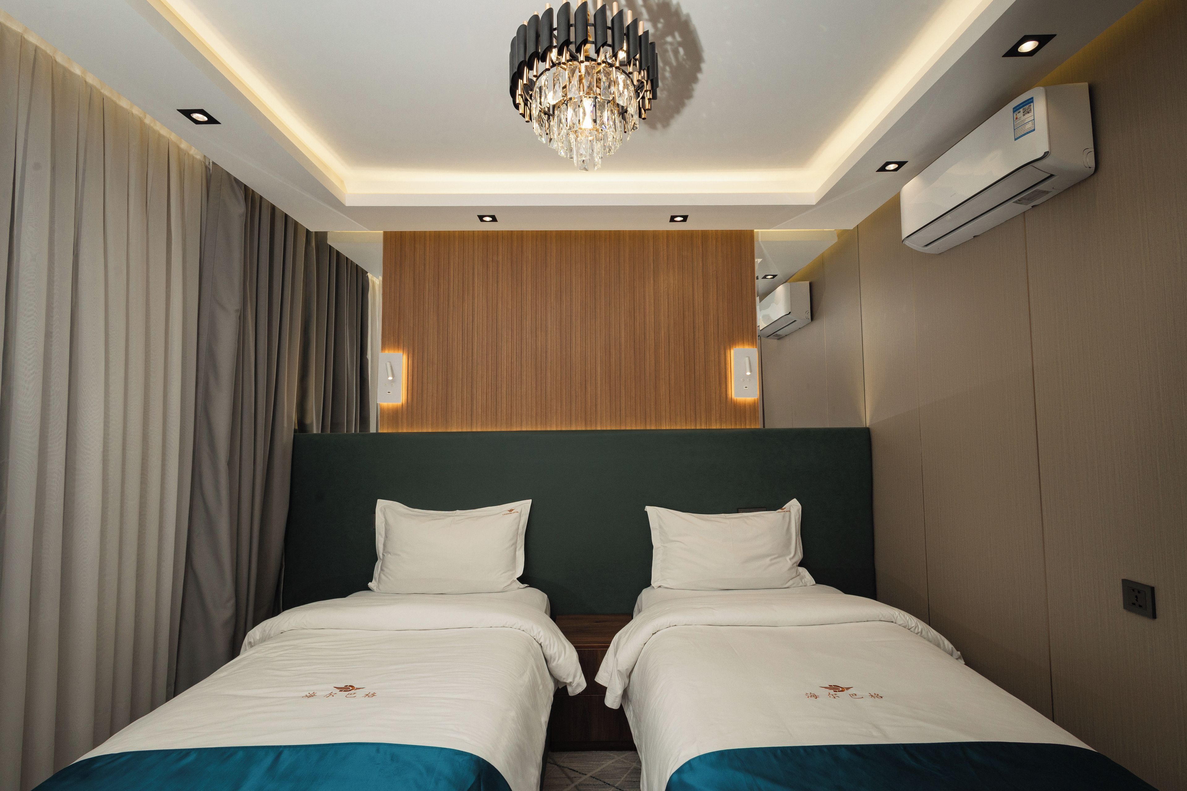 Une chambre d’hôtel avec un lit double, un lustre, un appareil de climatisation et un mur décoratif en bois.