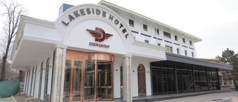 A Lakeside Hotel with a modern design, featuring a prominent entrance with glass doors and a curved facade.