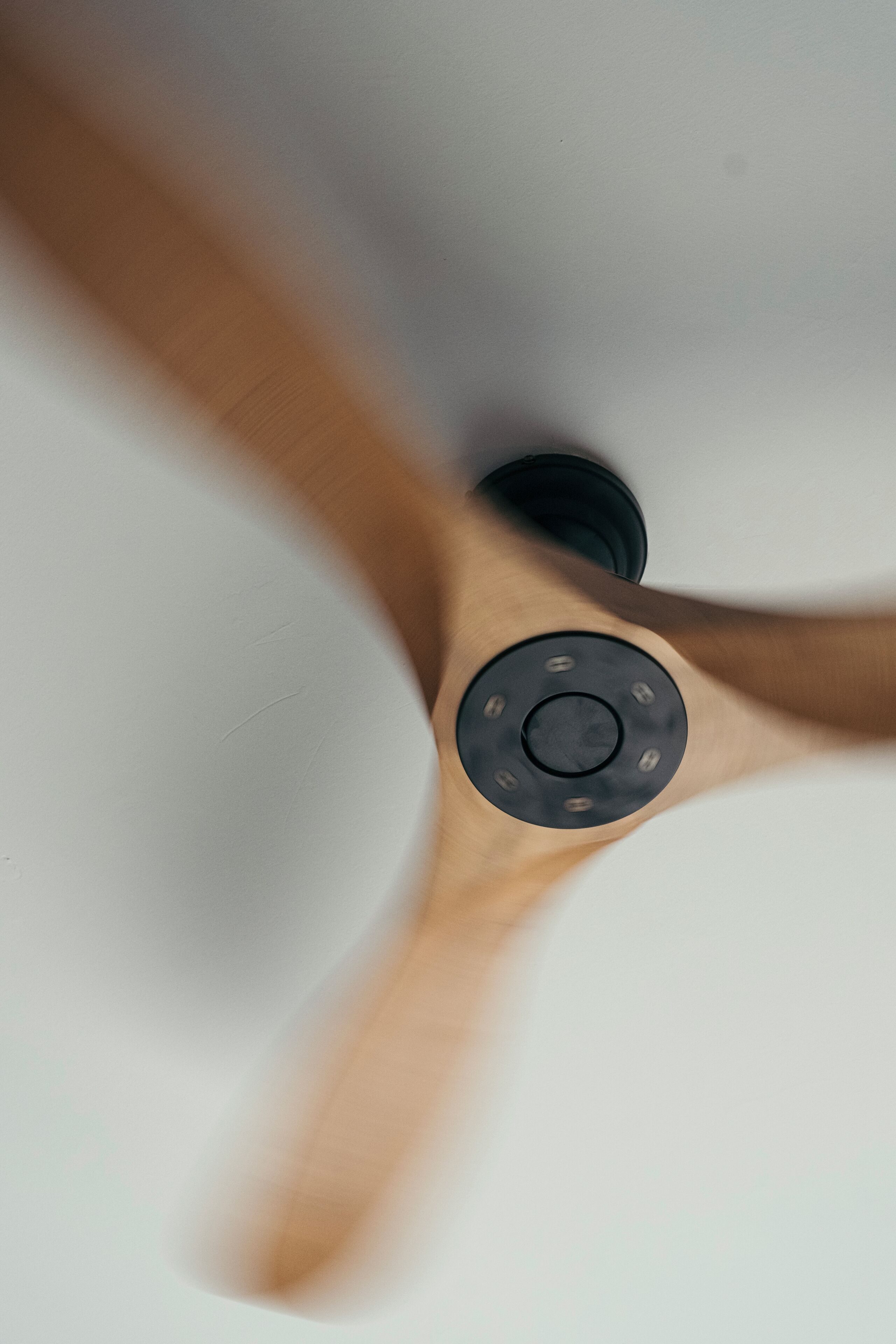 A ceiling fan with a wooden finish and a central control panel.