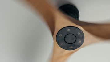 A ceiling fan with a wooden finish and a central control panel.