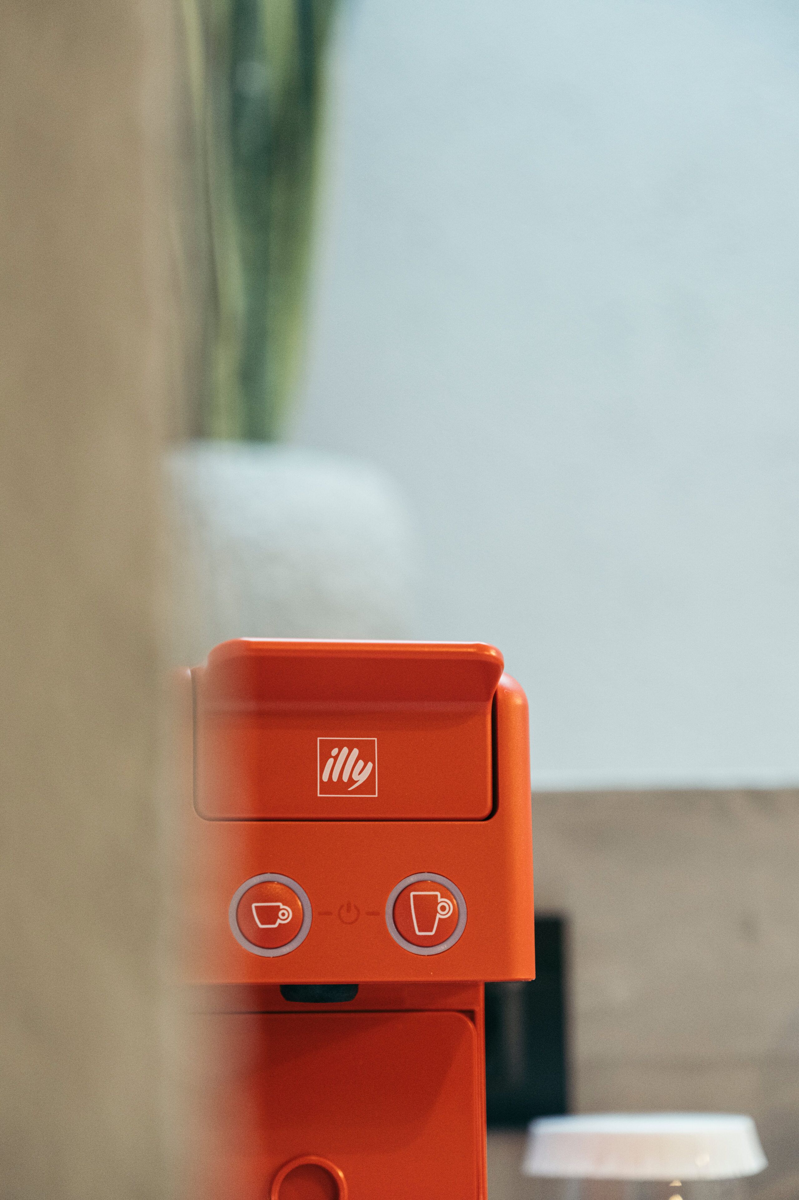 A red coffee machine with a logo, two buttons, and a power indicator.