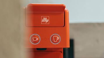 A red coffee machine with a logo, two buttons, and a power indicator.