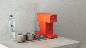 A kitchen counter with a coffee machine, a water bottle, and some containers.