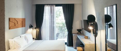 Een moderne hotelkamer met een bed, bureau en groot raam met gordijnen.
