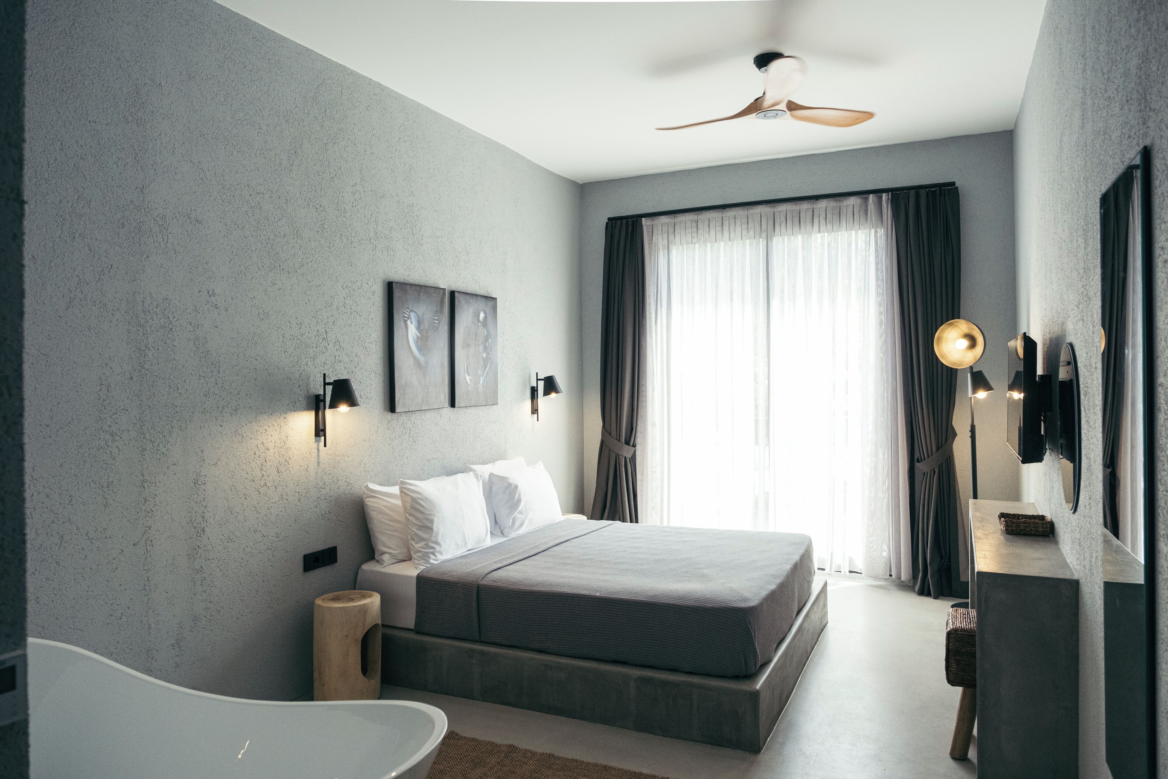 A modern bedroom with a bed, a bedside table, a lamp, and a ceiling fan.