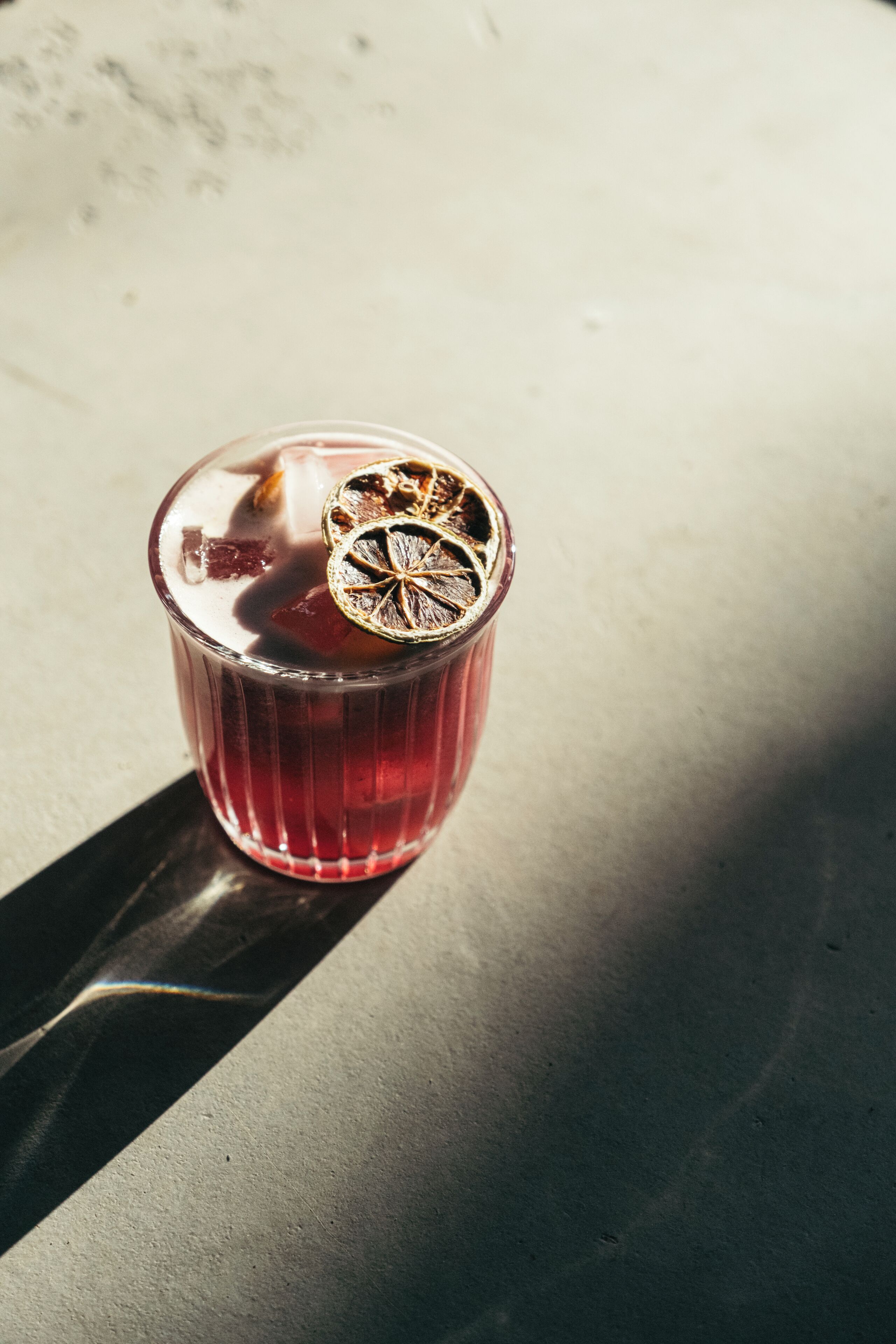 Een glas met een gedroogde bloemdecoratie op een reflecterend oppervlak.