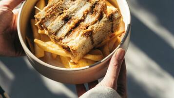 A person holding a bowl containing a sandwich and fries.