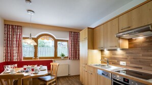 Eine kleine Küche mit Holzausstattung, einem Einbauofen und einem Fenster mit Vorhängen.