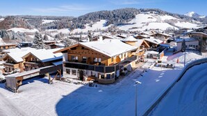 Ein schneebedecktes Dorf mit Holzbauten, darunter ein auffälliges Haus namens "Haus Daniela".