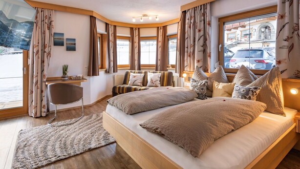 Ein modernes Schlafzimmer mit einem großen Bett, einem Sessel und Blick auf die Straße.
