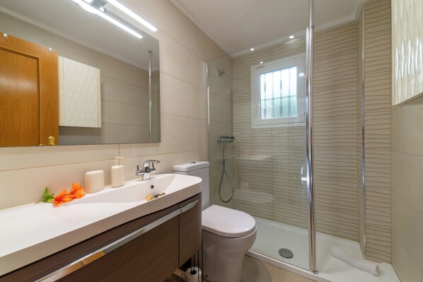 Une salle de bain moderne avec une douche à parois de verre, un lavabo blanc et des toilettes.