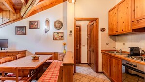 A cozy kitchen with wooden cabinets, a dining table with benches, and a tiled floor.