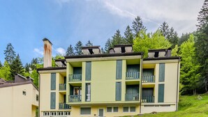 A multi-story building with balconies, a chimney, and a grassy hillside. - Nice apartment for 4 guests with TV, balcony and panoramic view (Ragoli)