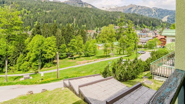 A balcony with a view of a town surrounded by mountains and dense forests. - Nice apartment for 4 guests with TV, balcony and panoramic view (Ragoli)
