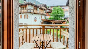 Un balcon doté de mobilier en bois, offrant une vue sur des bâtiments traditionnels et un arbre.