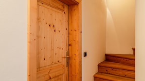 Une porte en bois dotée d’une poignée en laiton, qui donne sur un escalier en bois muni d’une main courante.