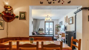 A cozy dining area with a wooden table and chairs, a chandelier, and butterfly wall decals. - Beautiful apartment for 6 guests with WIFI, TV and balcony (Spiazzo)