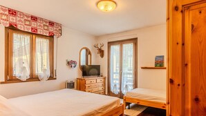 A bedroom with two beds, a TV, a mirror, and a wooden wardrobe. - Beautiful apartment for 6 guests with WIFI, TV and balcony (Spiazzo)