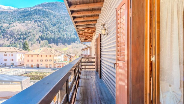 A wooden balcony with a view of a mountain and buildings in the background. - Beautiful apartment for 6 guests with WIFI, TV and balcony (Spiazzo)