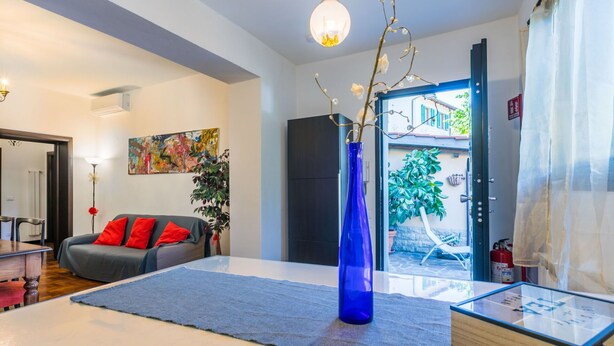 A modern living room with a sofa, a blue vase, and a glass coffee table. - Beautiful apartment for 5 guests with A/C, WIFI and patio (Greve In Chianti)