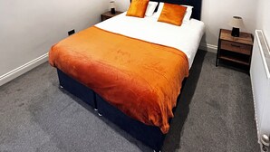 Una camera da letto con un letto, comodini, una lampada e un quadro appeso al muro.