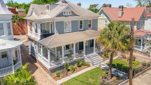 A two-story house with a porch, a covered front yard, and a small garden.