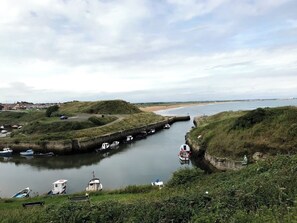 A coastal landscape with a canal, boats, and a beach.