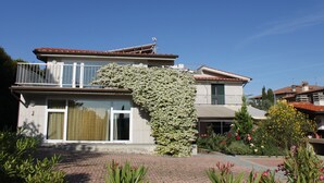 A two-story house with a balcony, a large window, and a garden with various plants and flowers. - Villa Bobolino, your Tuscan vacation with private pool (18 people) (Montelupo Fiorentino)