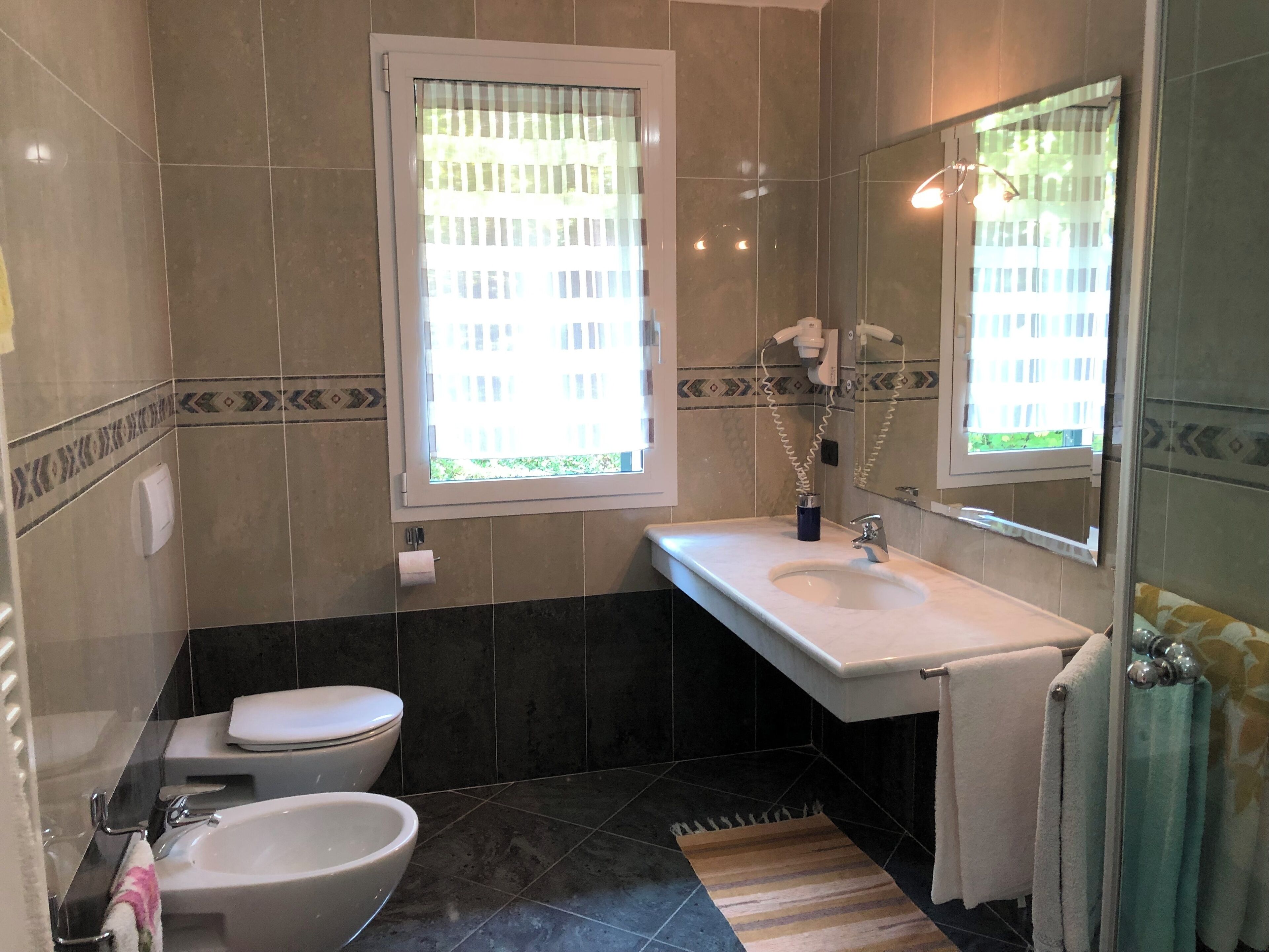 A bathroom with a toilet, bidet, sink, and mirror.