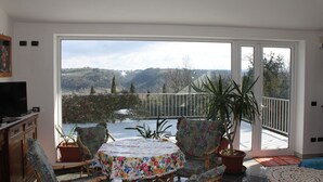 A balcony with a table and chairs, a potted plant, and a view of a mountainous landscape. - Villa Bobolino, your Tuscan vacation with private pool (18 people) (Montelupo Fiorentino)