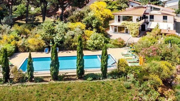 A residential property with a swimming pool surrounded by tall cypress trees, a garden with various plants, and a house with a tiled roof and balcony. - Villa Bobolino, your Tuscan vacation with private pool (18 people) (Montelupo Fiorentino)