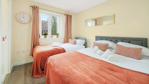 Habitación de hotel con dos camas, una ventana con cortinas, un reloj de pared y un espejo.