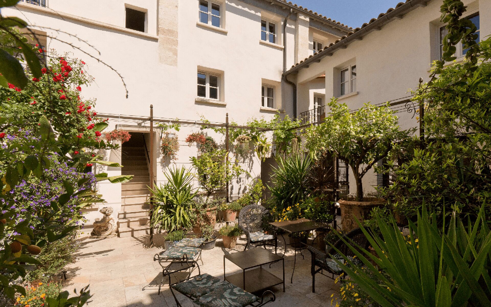 Une cour avec un sol en pierre, des meubles d’extérieur et des plantes en pot.