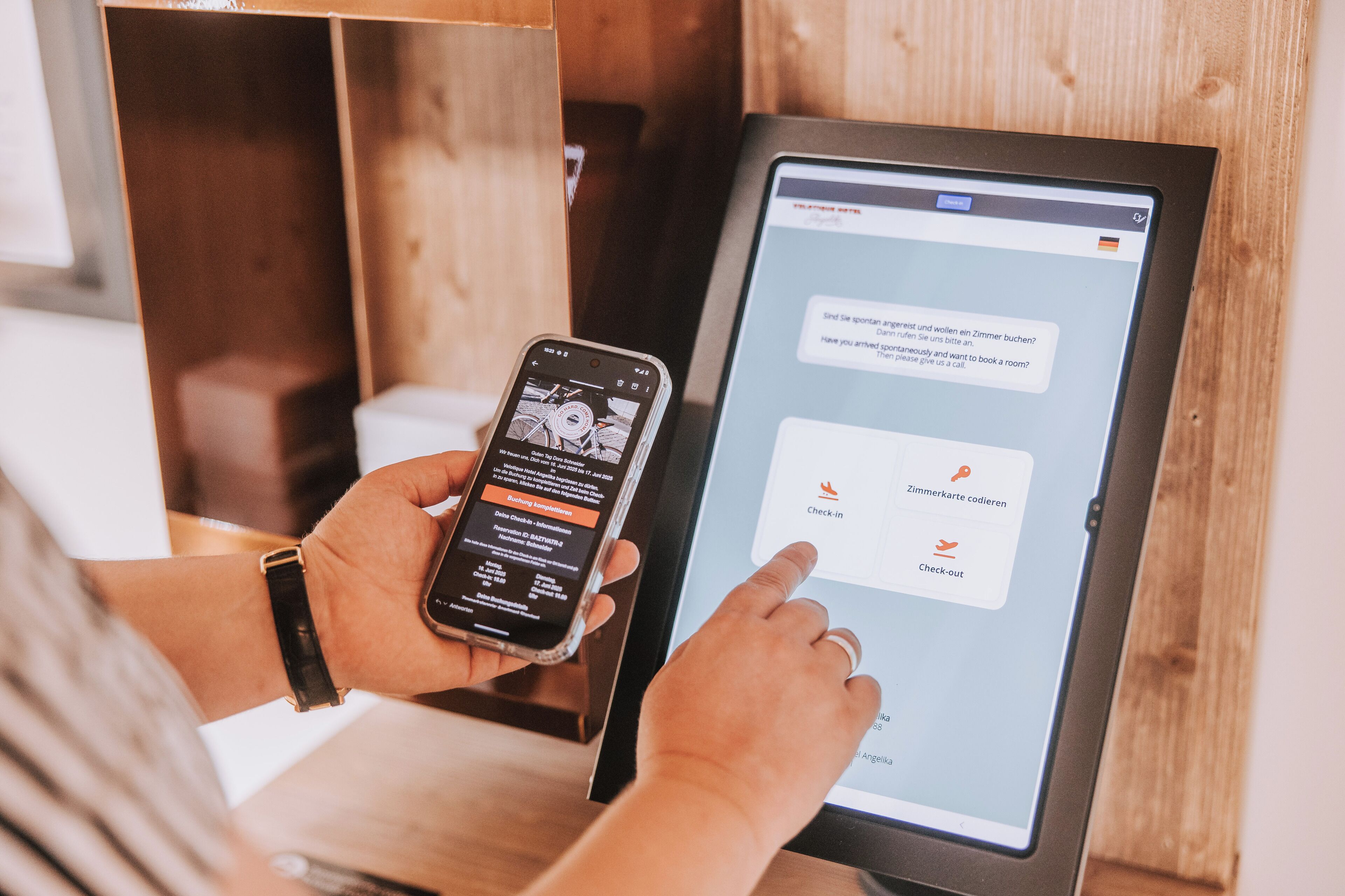 Eine Person benutzt ein Tablet, um eine digitale Benutzeroberfläche zu nutzen, vermutlich für die Hotelzimmerbuchung oder Check-in.