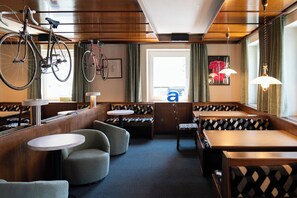 A restaurant with wooden booths, round tables, and bicycles hanging on the wall. - Velotique Hotel Angelika - Self-Check-in (Hard)